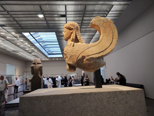 Sfinge greca con volto femminile, corpo, zampe e coda di leone, coperta di piume di uccello, di solito alata e in posizione seduta